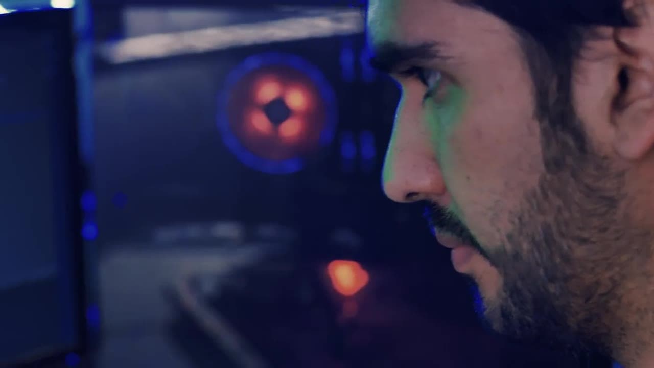 Illustrative stock film of a person working at a computer in a dark room lit by screens