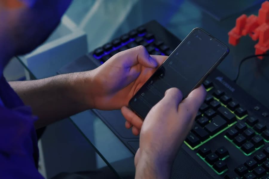 Illustrative stock photograph of hands holding a phone above a lit keyboard