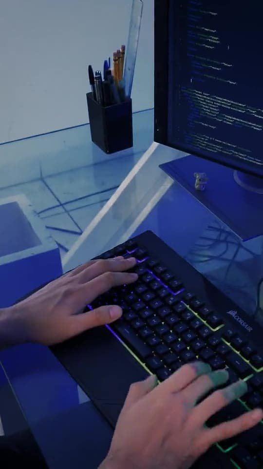 Illustrative stock film of hands typing on a lit keyboard beside a monitor