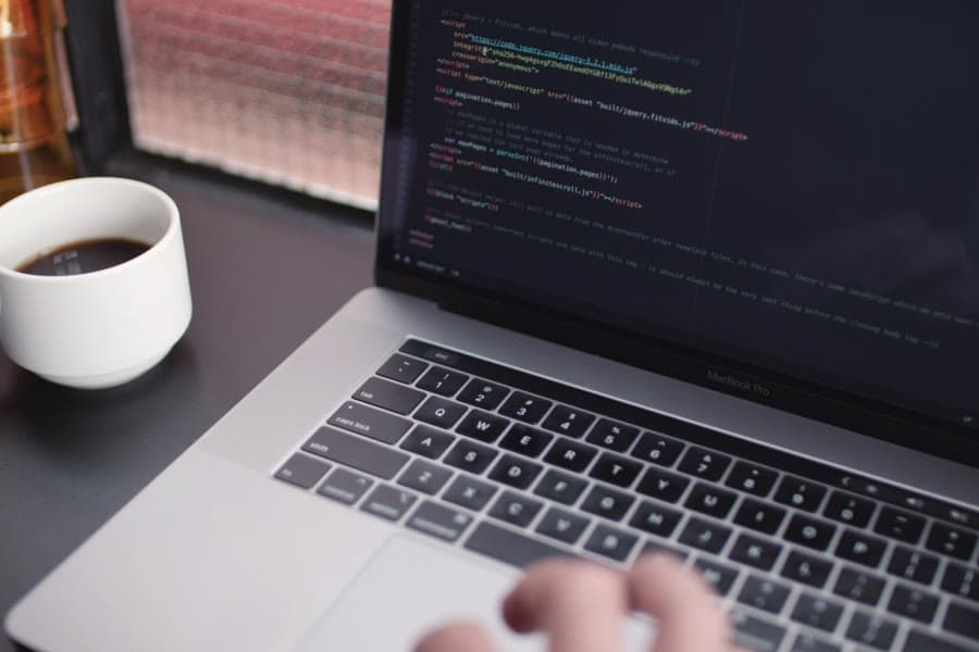 Illustrative stock photograph of a laptop showing code beside a cup of coffee