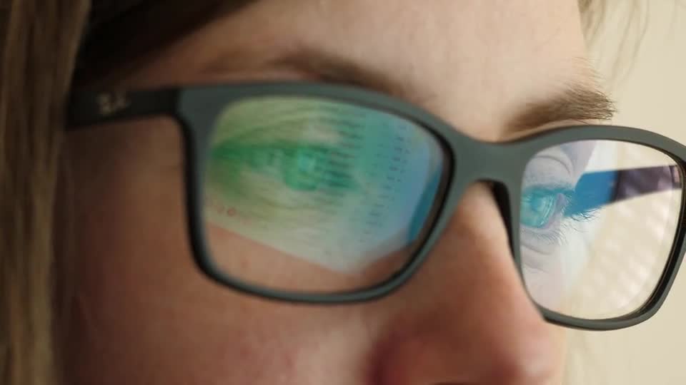 Illustrative stock film of a person seeing a screen reflected in their glasses