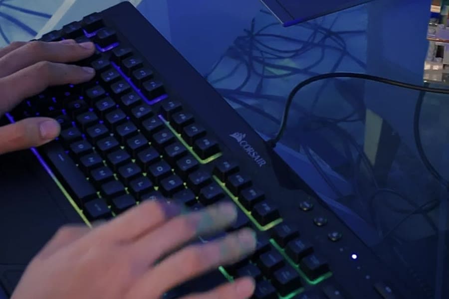 Illustrative stock photograph of hands typing on a lit keyboard at a desk